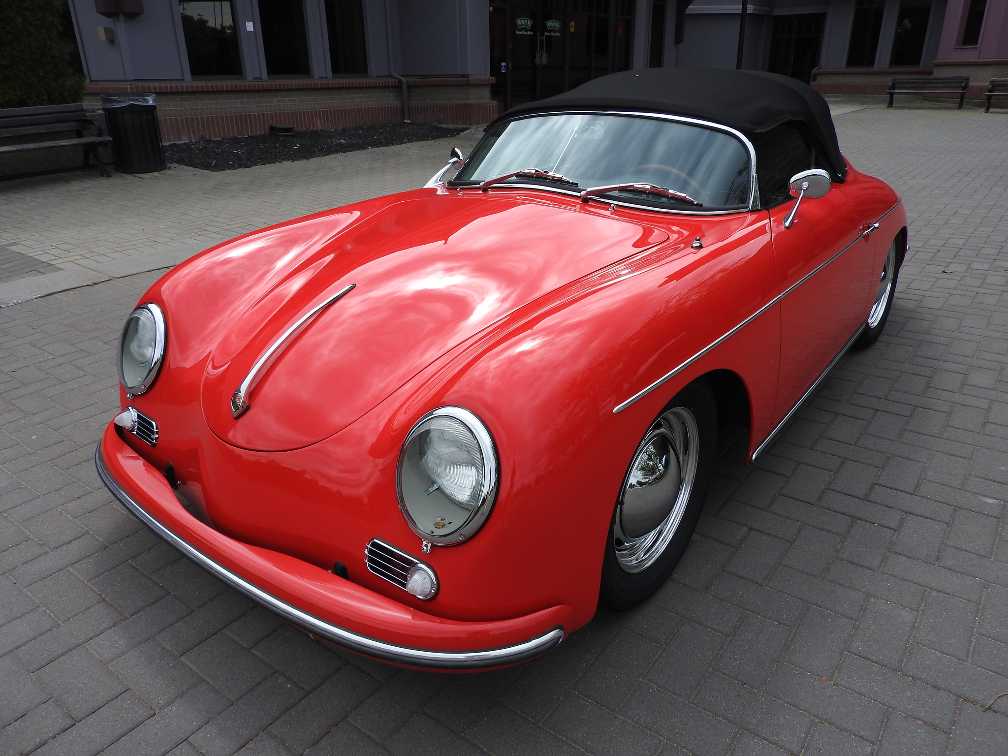 Red Intermeccanica Speedster with Black Convertible Top sits on cobbled plaza